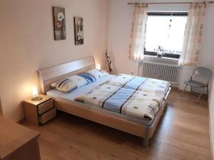 um quarto com uma cama, uma janela e uma cadeira em Ferienwohnung Fürst em Mauth
