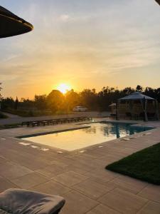 a pool with benches and the sunset in the background at Le stanze di chiara in Torre Lapillo