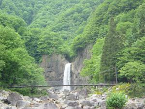 a bridge over a river with a waterfall at Park Lodge Sekine in Myoko