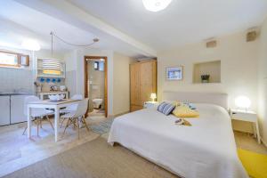 ein Schlafzimmer mit einem weißen Bett und einem Tisch sowie eine Küche in der Unterkunft Apartment Sympa in Dubrovnik