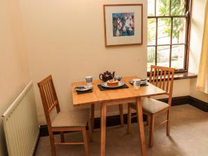 un tavolo in legno con sedie e un piatto di cibo sopra di The Coach House ad Allanton