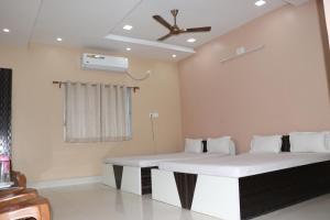 two beds in a room with a ceiling fan at Somani Inn in Jhārgrām