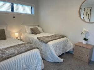 a bedroom with two beds and a mirror at Modern apartment- rural outlook, central Cambridge in Cambridge