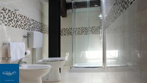 uma casa de banho com um WC e uma cabina de duche em vidro. em Le Saline Rooms Marzamemi em Marzamemi