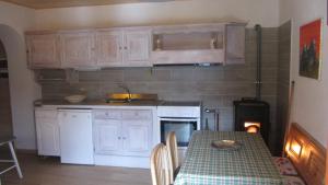 a kitchen with white cabinets and a table and a stove at Baita cavalese giardino esclusivo in Cavalese