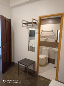 a bathroom with a toilet and a table and a mirror at 8 Zhensen Inn in Bacoor