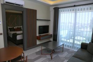 a living room with a bed and a room with a television at Güven Park Residance & Apart Hotel in Kemer
