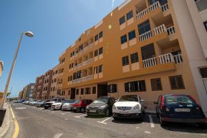 a row of cars parked in a parking lot in front of a building at alquilaencanarias El Medano Playa El Cabezo in El Médano