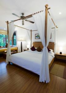 a bedroom with a white bed with a canopy at Kuramathi Maldives in Rasdhoo