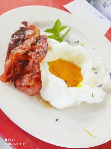 un piatto di cibo con un uovo fritto e pancetta di Hotel Garisenda B&B - in Centro a Riccione - a Riccione