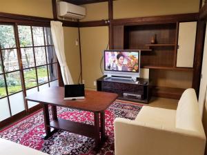 a living room with a television and a table with a laptop at コンドミニアム津和野荘 in Tsuwano