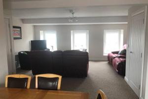 a living room with a black couch and a table and chairs at Beautiful Sea view, Entire 2 bed Apartment, Portrush centre West Strand BeachView in Portrush