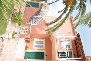 een roze huis met een groene deur en palmbomen bij Marilena Apartments in Sidari