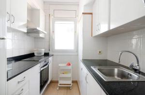 a kitchen with white cabinets and a sink and a window at Precioso apartamento en primera línea de mar en Calella de Palafrugell in Calella de Palafrugell