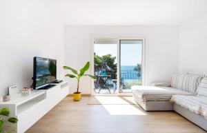 een witte woonkamer met een bank en een tv bij Precioso apartamento en primera línea de mar en Calella de Palafrugell in Calella de Palafrugell