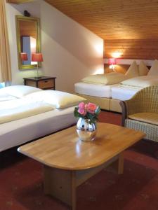 a hotel room with two beds and a table with flowers on it at Sportpension Thayer in Piesendorf