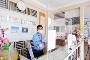 a man wearing a face mask stands in a room at Blitz Hotel Batam Centre in Batam Center