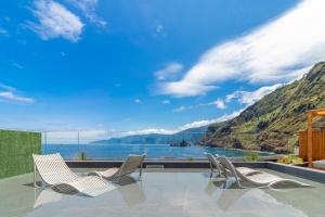 a patio with two chairs and a view of the water at Aqua Natura Bay in Porto Moniz