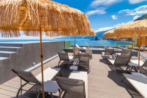 a deck with chairs and umbrellas on the beach at Aqua Natura Bay in Porto Moniz