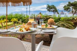 a table with two plates of food and glasses of wine at Aqua Natura Bay in Porto Moniz
