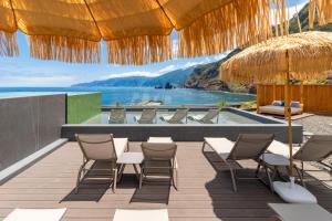 an outdoor patio with chairs and a swimming pool at Aqua Natura Bay in Porto Moniz