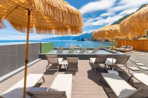 a resort with a pool and chairs and an umbrella at Aqua Natura Bay in Porto Moniz