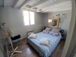 a bedroom with a bed with a mirror and a chair at Maison de pecheur in Sigean