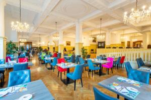 un restaurant avec des tables bleues et des chaises colorées dans l'établissement Hotel Badehof, à Bad Salzschlirf