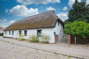 a white house with a thatched roof at wassernahes Haus mit Terrasse und Garten - Ferienhaus Storchennest Haus rechte Seite in Wiek auf Rügen  +13 photos