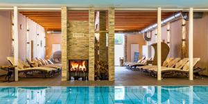 a hotel lobby with a pool and chairs and a fireplace at Hotel Badehof in Bad Salzschlirf