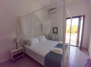 une chambre avec un lit blanc à baldaquin dans l'établissement ANCIENT MEROPIA - Eden, à Apollonia