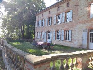 un bâtiment en briques avec une table et des chaises devant lui dans l'établissement Le Jardin Des Cèdres, à Lavaur