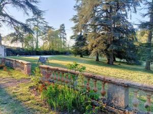 un jardin avec une clôture en briques et des arbres dans l'établissement Le Jardin Des Cèdres, à Lavaur