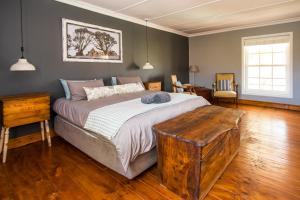 a bedroom with a large bed and a wooden floor at Avondrust Guest House in Klaarstroom