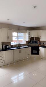 cocina con armarios blancos y suelo de baldosa blanca en Modern Home Carndonagh en Carndonagh