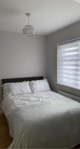 a white bed in a bedroom with a window at Modern Home Carndonagh in Carndonagh