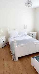 a white bedroom with a white bed and two night stands at Modern Home Carndonagh in Carndonagh