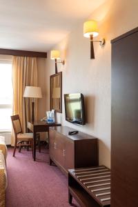 a hotel room with a bed and a tv and a desk at Hotel MOP Oleśnica Mała in Oleśnica Mała