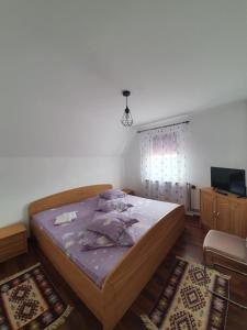 sypialnia z łóżkiem z fioletową pościelą i telewizorem w obiekcie Casa Daria Ranca w mieście Rânca