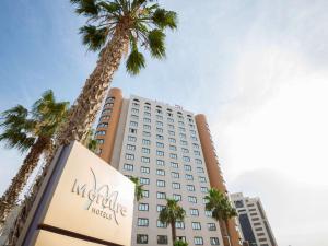 a hotel with palm trees in front of it at Hotel Mercure Alger Aéroport in Dar el Beïda