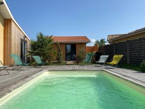 a small swimming pool with chairs and a house at L'annexe in Le Teich