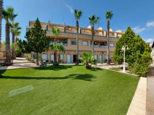 een gebouw met palmbomen en een gazon bij Hotel Costa Blanca Rojales in Rojales