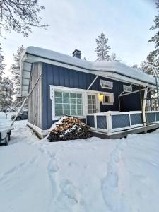 una casa blu con un mucchio di legno nella neve di Ojuspirtti 26A Levi a Levi