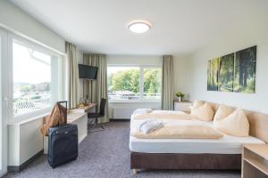 a hotel room with two beds and a desk at Landhotel Kristall in Bad Marienberg