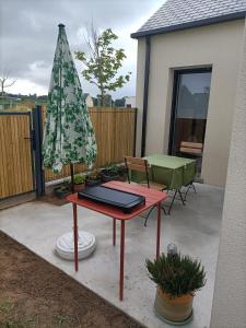 une terrasse avec une table et un parasol dans l'établissement Proche GR34 , Studio "Estrella" , petit cocon accueillant, à Hillion