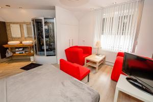 a living room with red chairs and a television at B & B M 3 in Merkelbeek