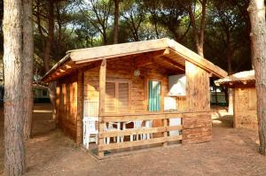 une cabane en bois avec une clôture et un arbre dans l'établissement Camping Bella Sardinia, à S'archittu Cuglieri