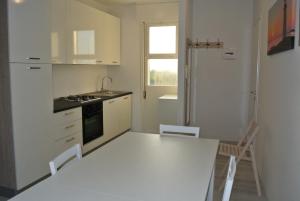 een witte keuken met een witte tafel en stoelen bij DUNA 4 in Lignano Sabbiadoro