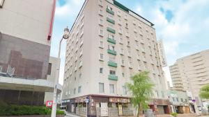 新潟市にあるホテルクラウンヒルズ新潟のヤシの木が目の前にそびえる白い高い建物