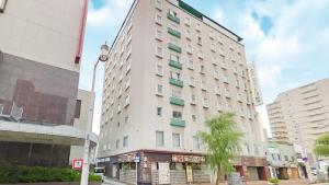 a tall white building with a palm tree in front of it at Hotel Crown Hills Niigata in Niigata